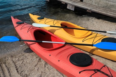 Modern kayaks with paddles on beach near river. Summer camp activity