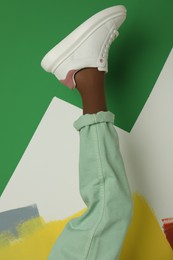 Photo of Woman wearing sneakers on color background, closeup