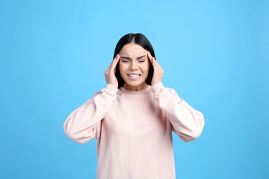 Portrait of stressed young woman on light blue background