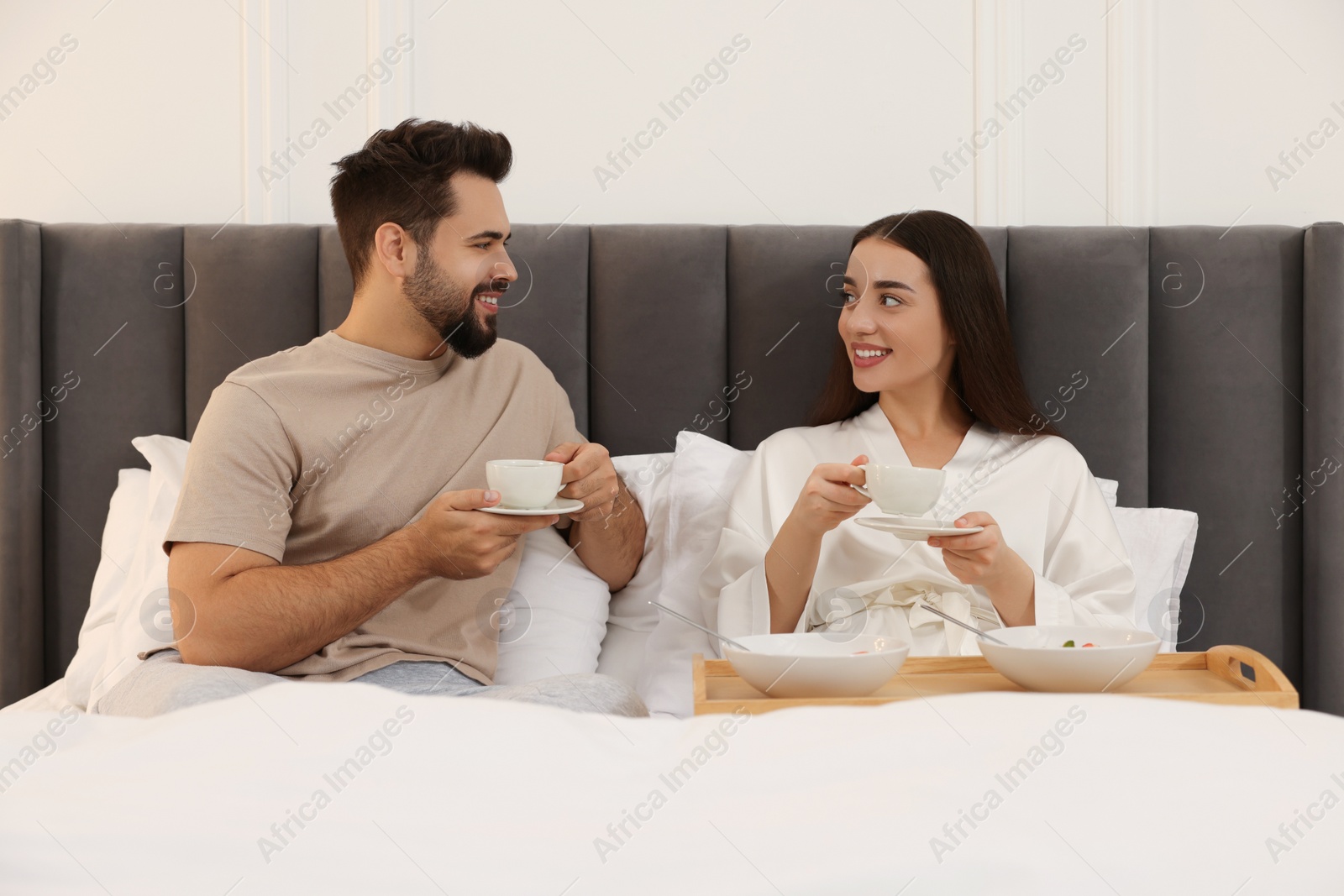 Photo of Happy couple having breakfast on bed at home