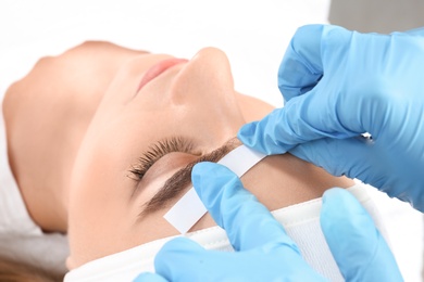 Young woman having professional eyebrow correction procedure in beauty salon