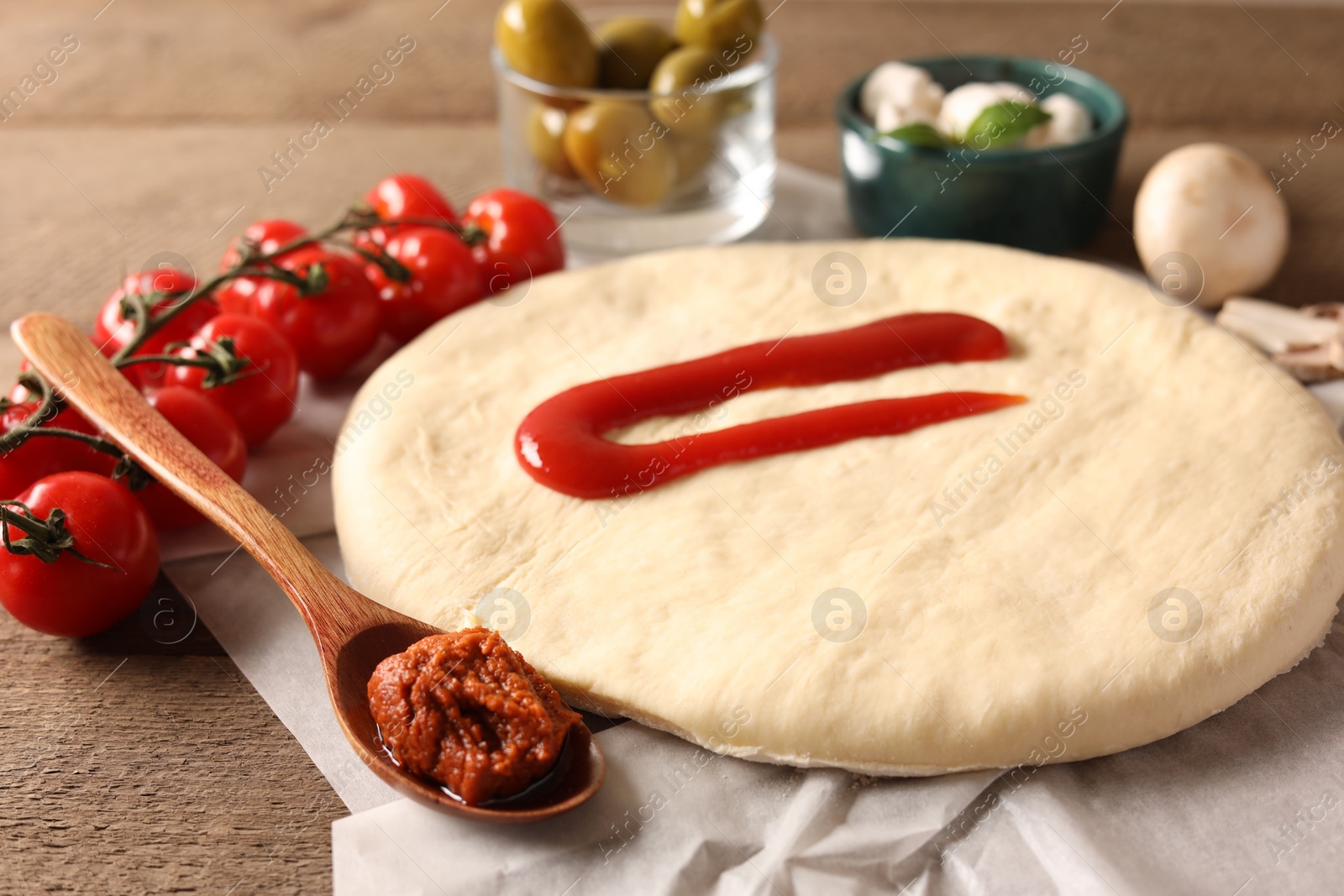 Photo of Pizza dough and products on wooden table, closeup