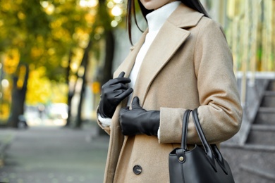 Photo of Woman with leather gloves and stylish bag on city street, closeup