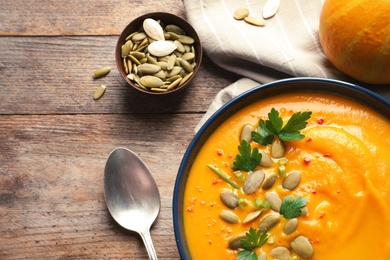 Photo of Flat lay composition with delicious pumpkin cream soup in bowl on wooden background