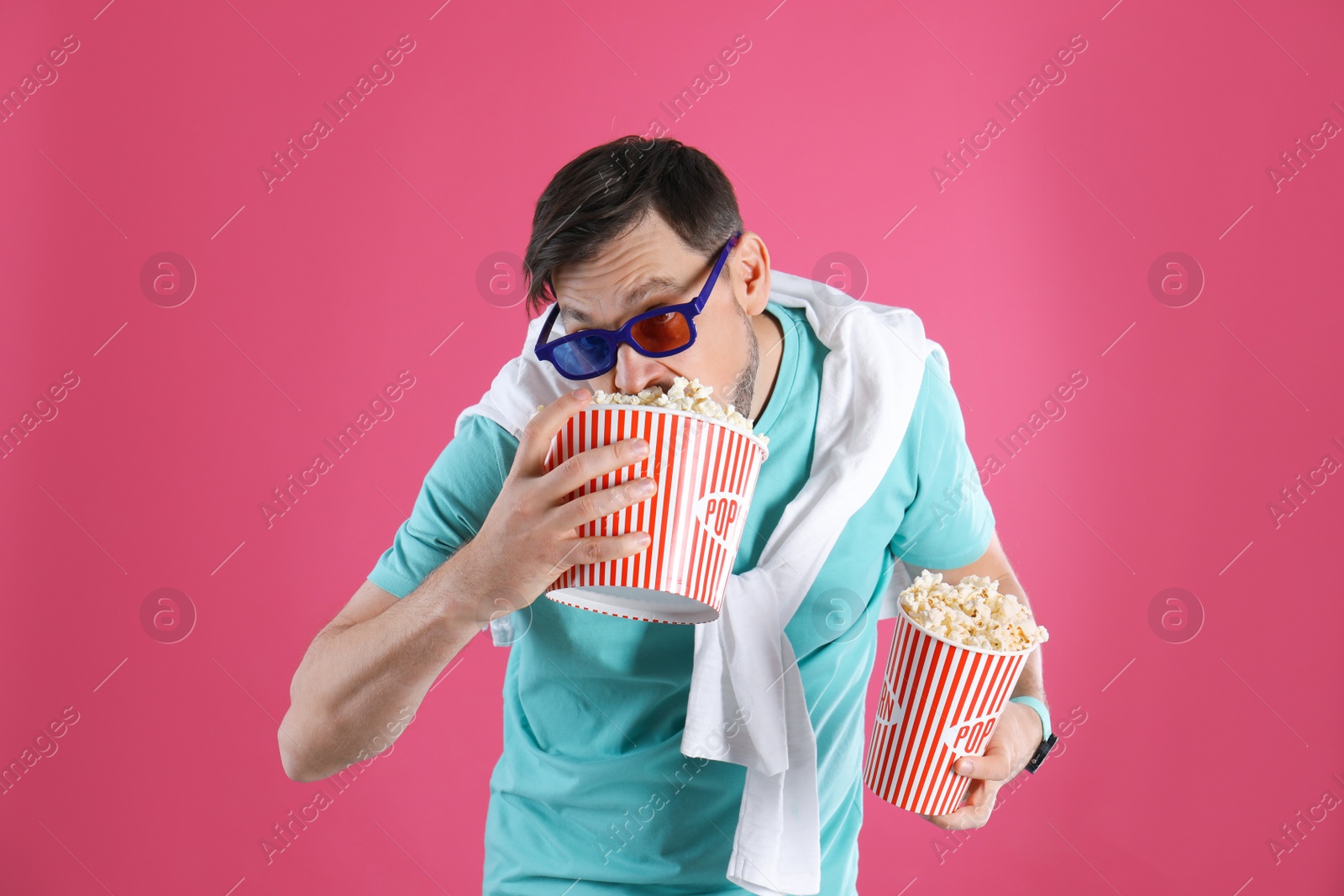 Photo of Man with 3D glasses eating tasty popcorn on color background
