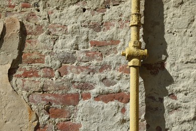 Photo of Yellow gas pipe on old brick wall outdoors, space for text