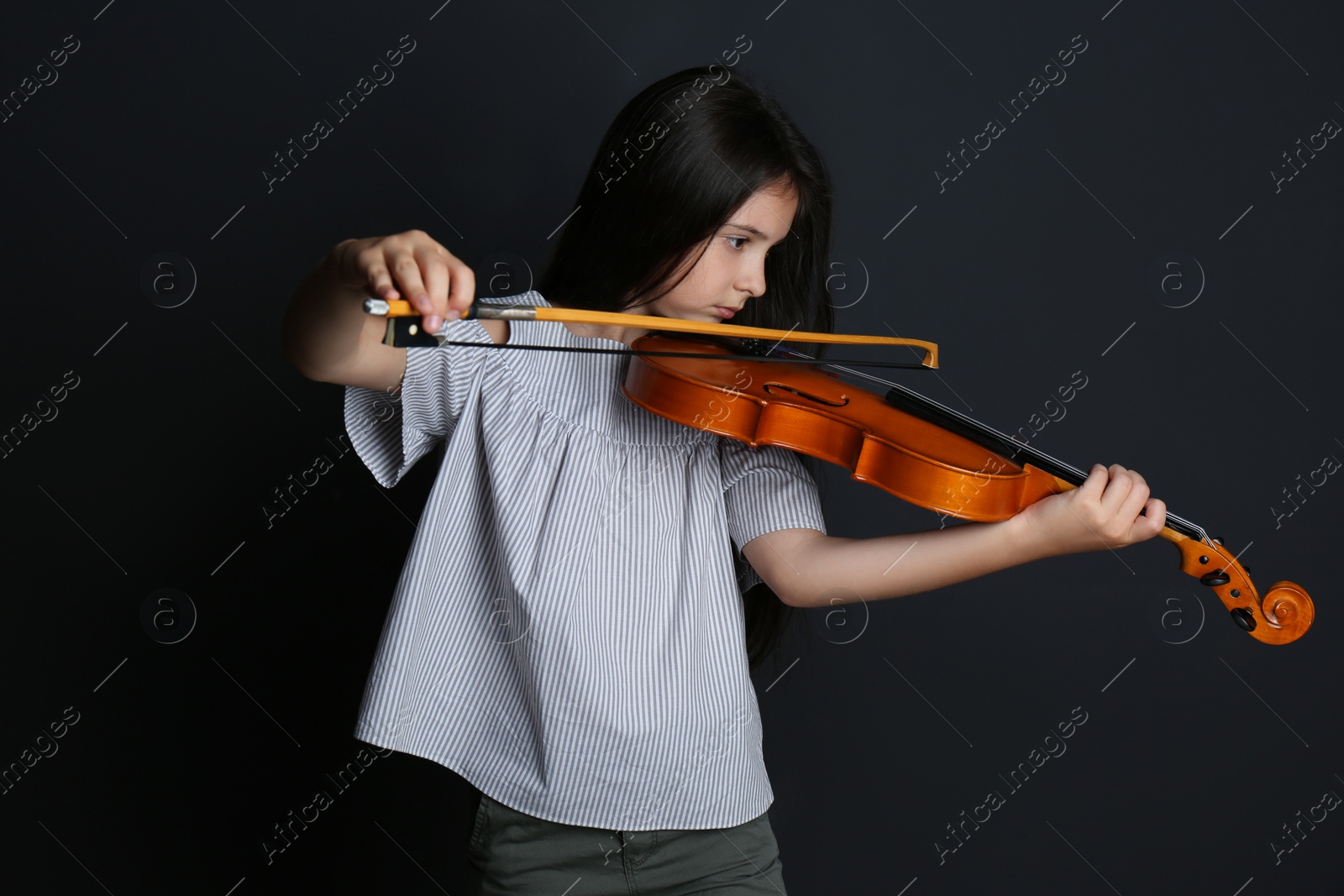 Photo of Preteen girl playing violin on black background