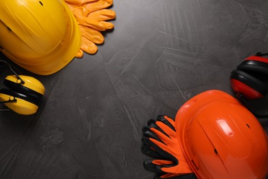 Photo of Hard hats, gloves and earmuffs on grey table, flat lay with space for text. Safety equipment