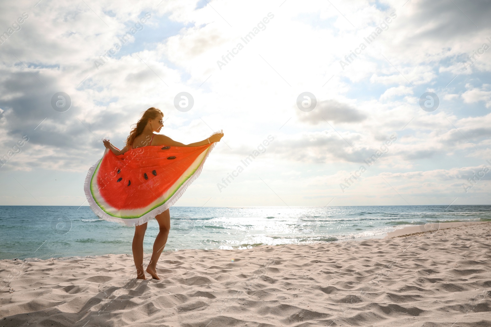 Photo of Beautiful woman with bright beach towel on sunlit seashore