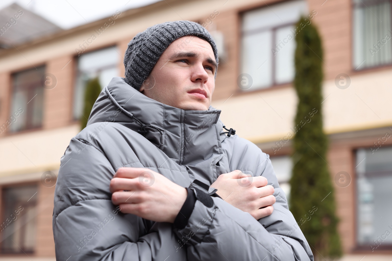 Photo of Sick young man in warm clothes on city street