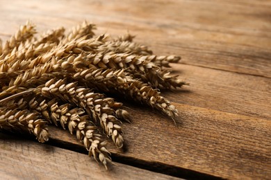 Many ears of wheat on wooden table, closeup