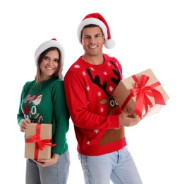 Beautiful happy couple in Santa hats and sweaters holding Christmas gifts on white background