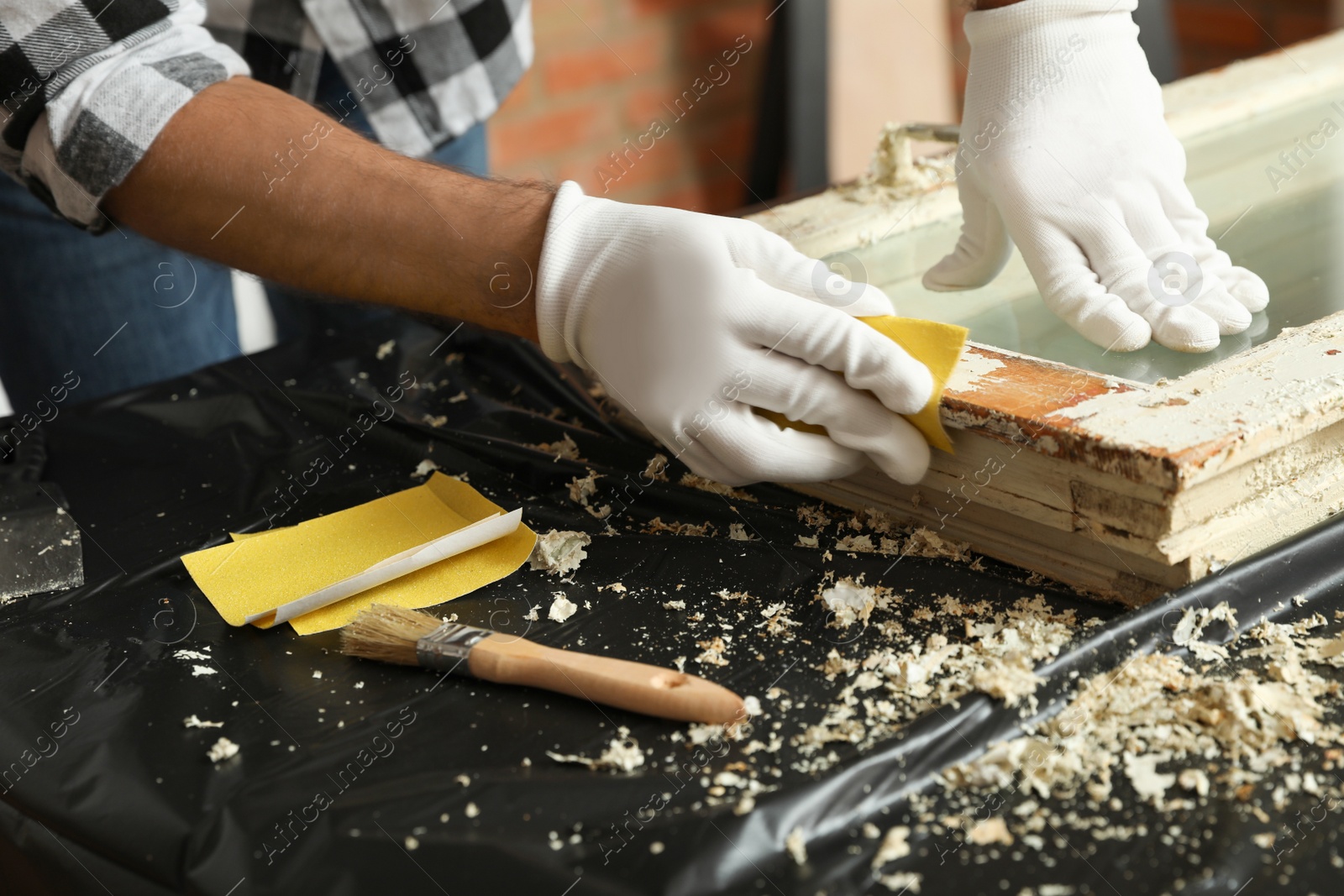 Photo of Man repairing old damaged window at table indoors, closeup