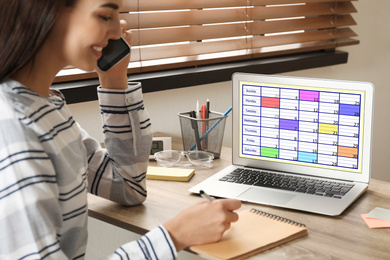 Photo of Young woman planning her schedule with calendar app on laptop in office