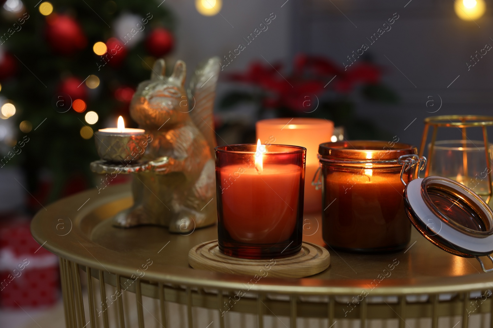 Photo of Burning candles on table in room decorated for Christmas