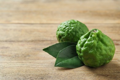 Fresh ripe bergamot fruits and leaves on wooden table, space for text