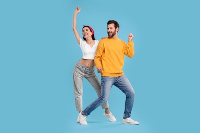Happy couple dancing together on light blue background