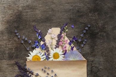Photo of Flat lay composition with beautiful dried flowers in envelope on wooden background, space for text