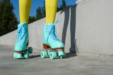 Young woman with retro roller skates in city on sunny day, closeup