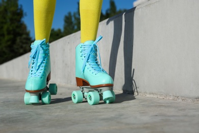 Photo of Young woman with retro roller skates in city on sunny day, closeup