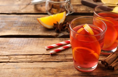 Photo of Aromatic punch drink and ingredients on wooden table. Space for text