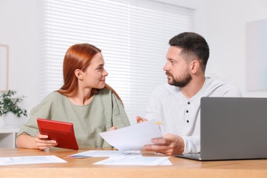 Couple calculating taxes at table in room