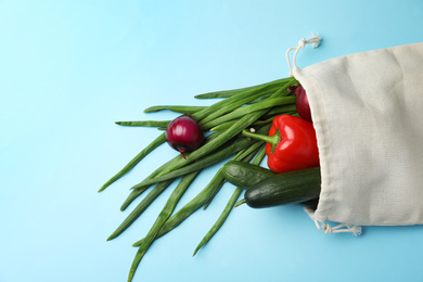 Photo of Cotton eco bag with vegetables on light blue background, top view