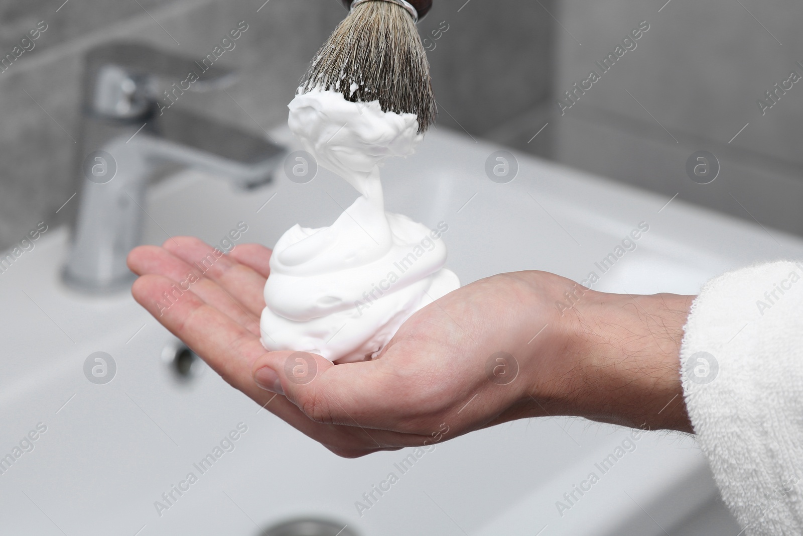 Photo of Man applying shaving foam onto brush in bathroom, closeup