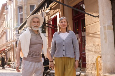 Photo of Affectionate senior couple walking outdoors, space for text
