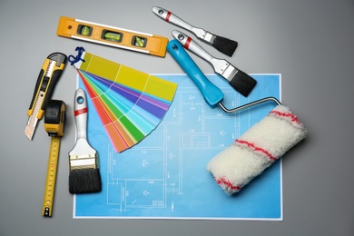 Set of decorator's tools and project drawing on grey background