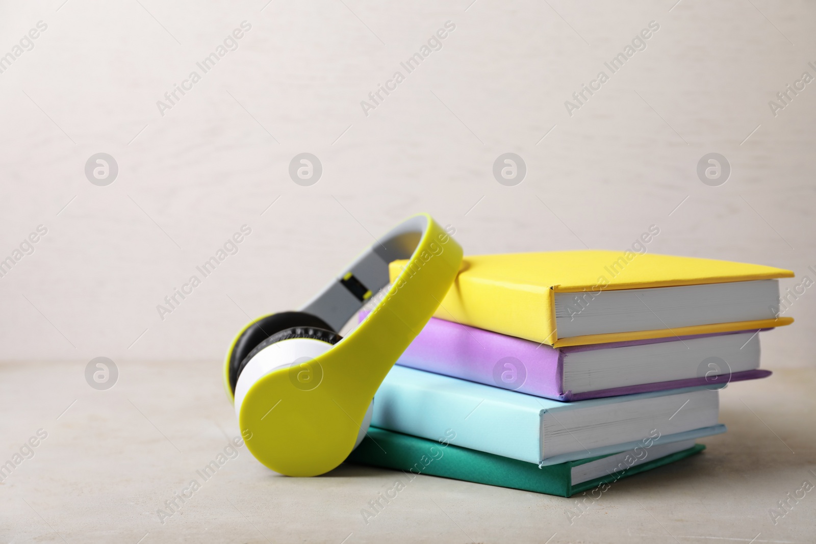 Photo of Modern headphones with hardcover books on grey table. Space for text