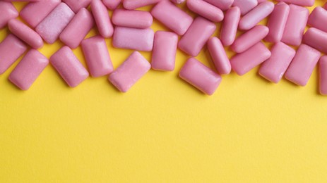 Photo of Sweet chewing gums on yellow background, flat lay. Space for text