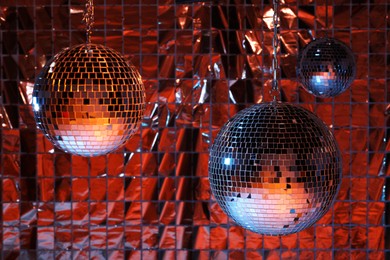 Shiny disco balls against foil party under color lights