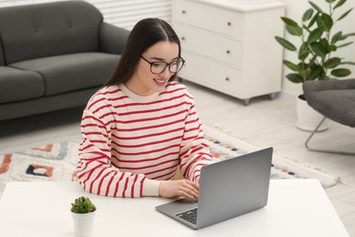 Woman using laptop at white table indoors