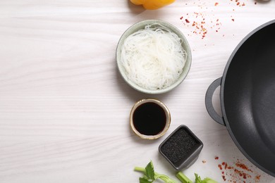 Photo of Wok and different products on white wooden table, flat lay. Space for text