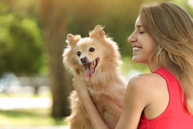 Young woman with her cute dog in park, space for text