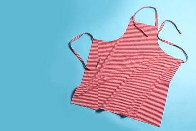 Striped apron on light blue background, top view. Space for text