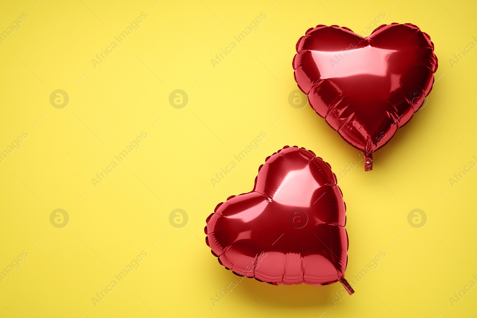 Photo of Red heart shaped balloons on yellow background, flat lay with space for text. Valentine's Day celebration