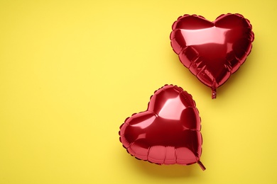 Photo of Red heart shaped balloons on yellow background, flat lay with space for text. Valentine's Day celebration