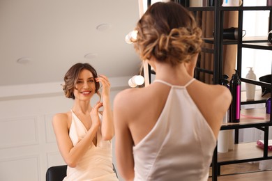 Photo of Woman with beautiful hairstyle near mirror in salon
