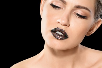 Beautiful young model with creative lips makeup on black background