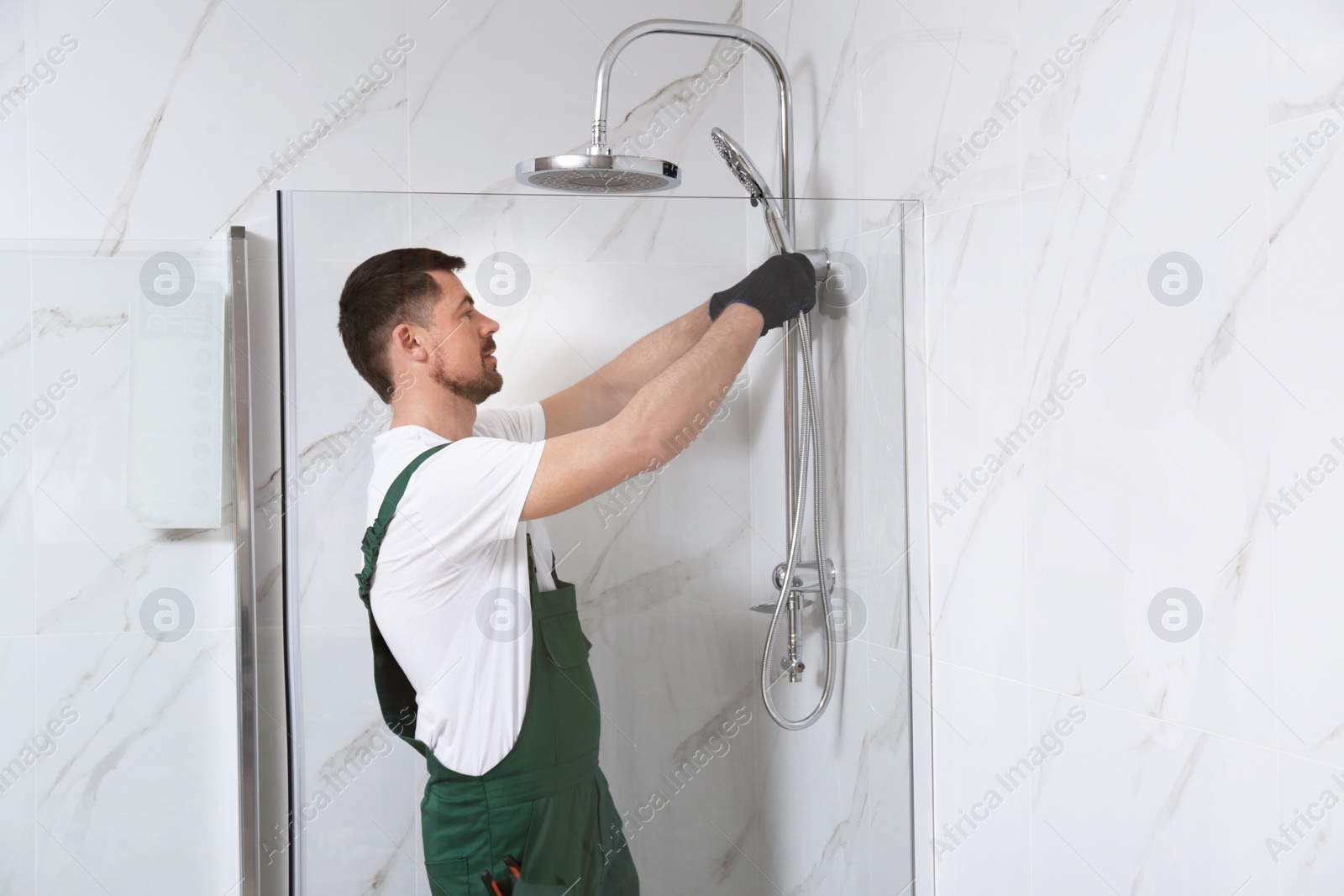 Photo of Professional handyman working in shower booth indoors