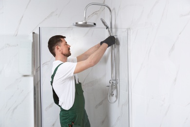 Photo of Professional handyman working in shower booth indoors