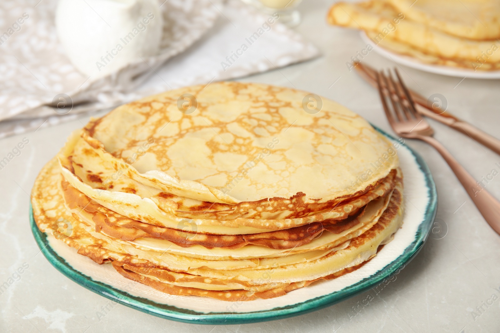 Photo of Stack of fresh thin pancakes on light grey marble table