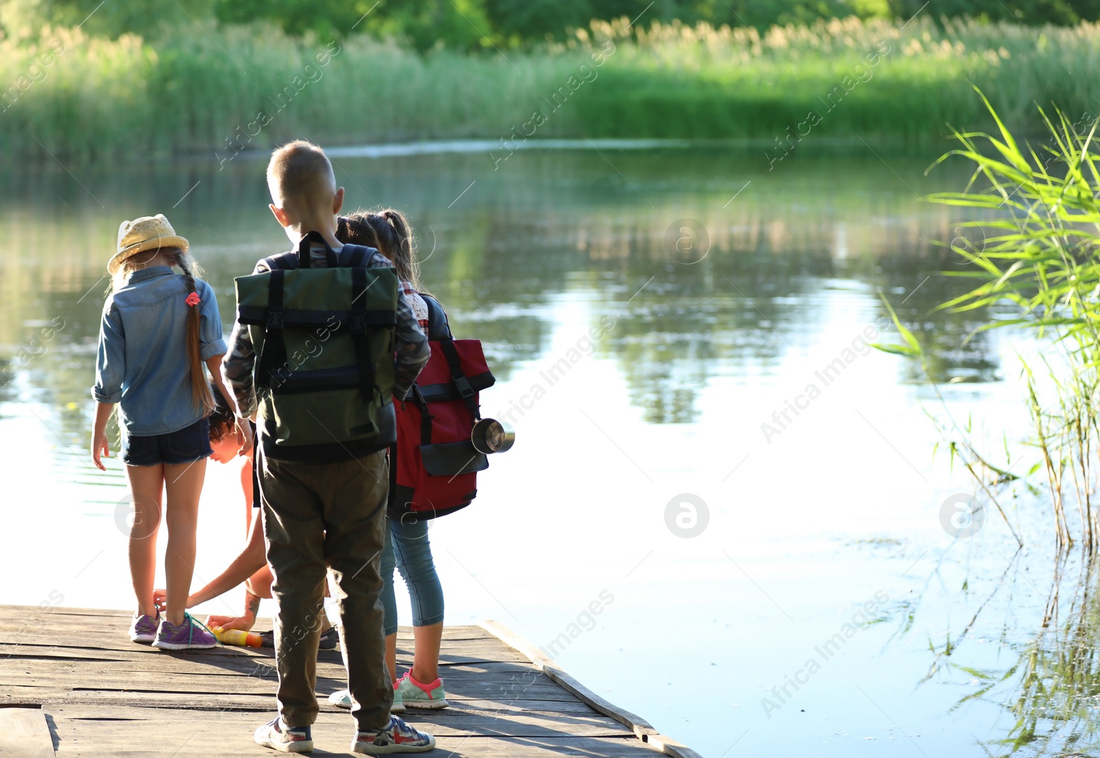 Photo of Little children on wooden pier. Summer camp