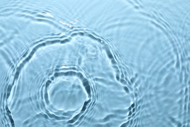 Rippled surface of clear water on light blue background, top view