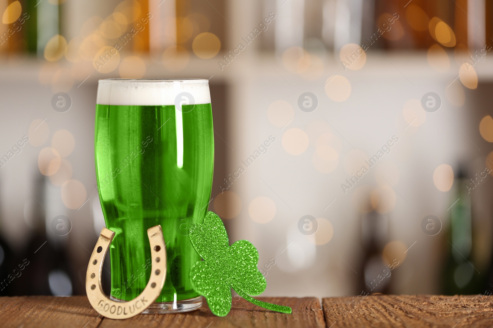 Photo of Green beer, horseshoe and clover on wooden counter, space for text. St.Patrick's Day celebration