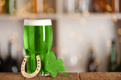 Green beer, horseshoe and clover on wooden counter, space for text. St.Patrick's Day celebration