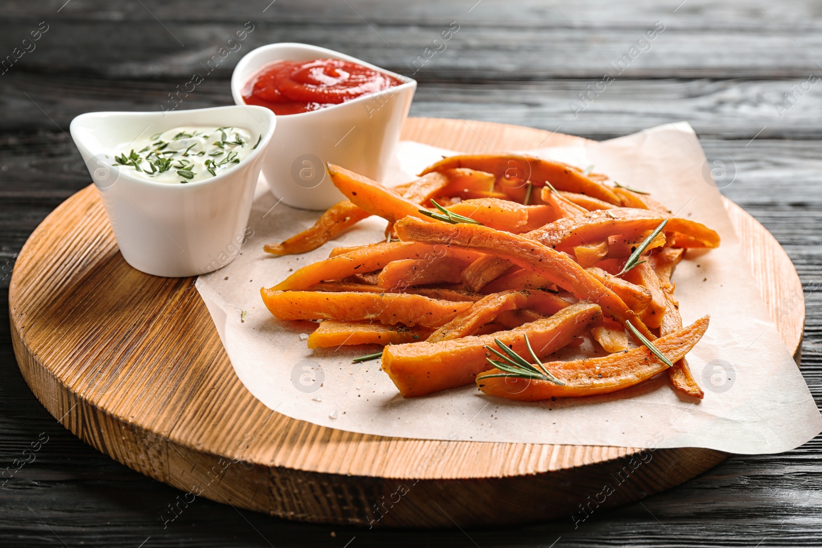 Photo of Board with sweet potato fries and sauces on wooden table