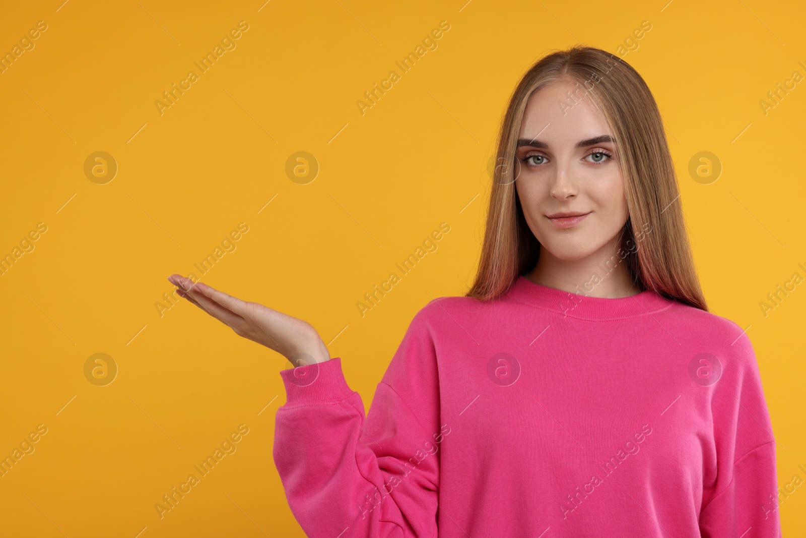 Photo of Special promotion. Young woman showing something on orange background, space for text